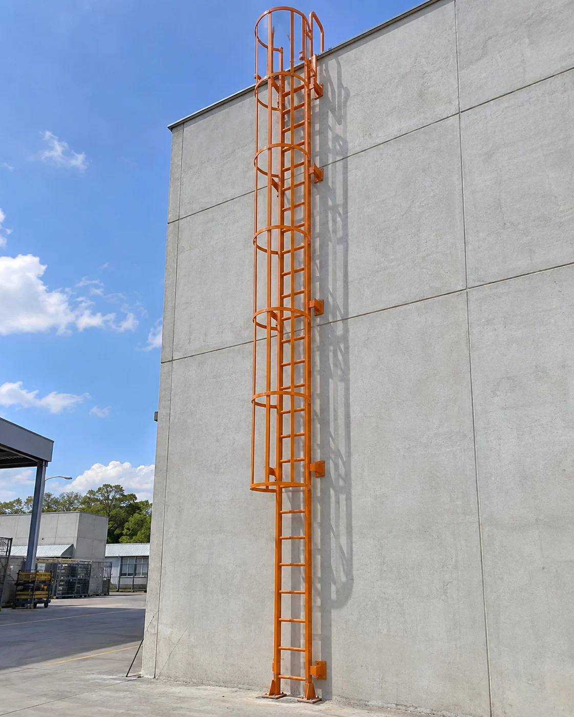 Escada vertical laranja com aros de proteção em fachada industrial